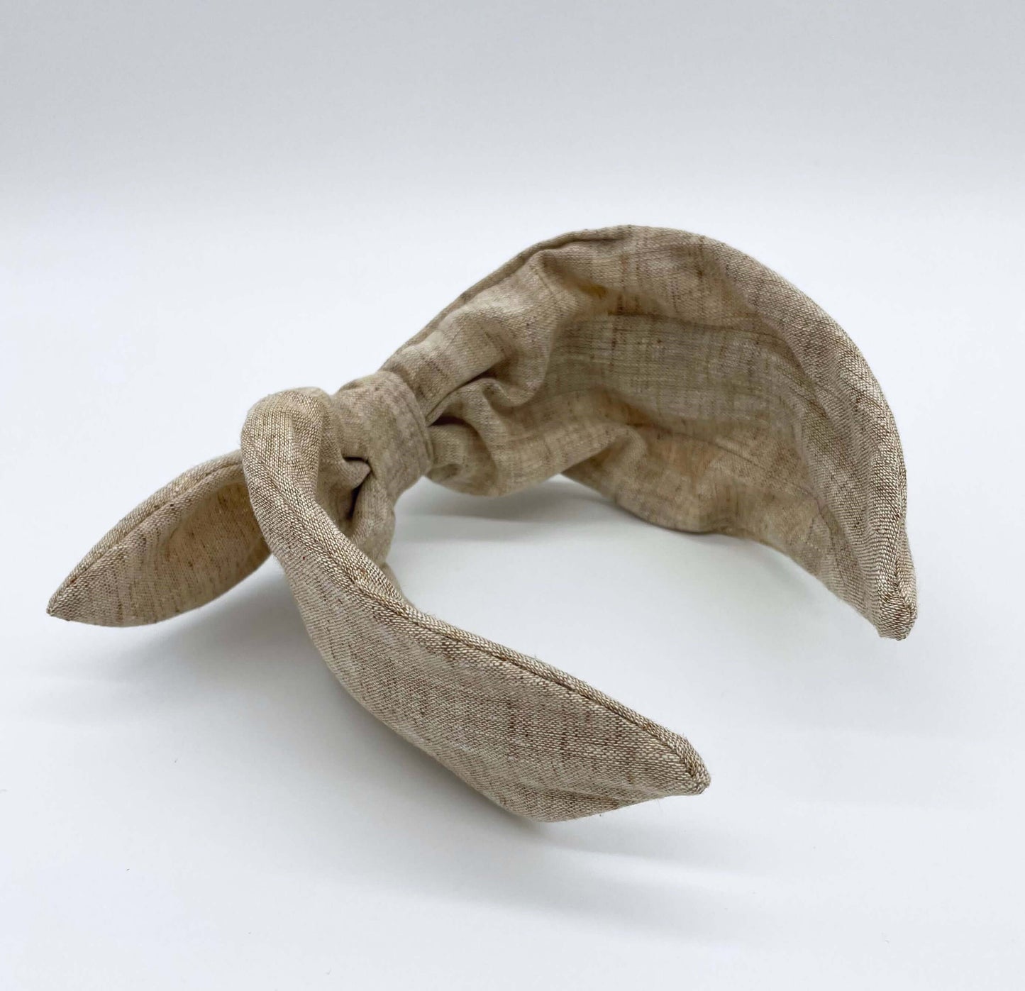 A natural coloured linen headban with a bow.