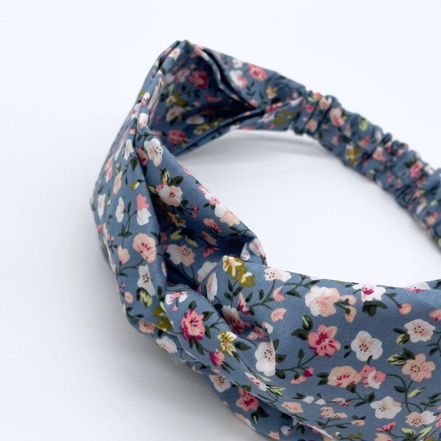 A pink, blue and white ditsy print elasticated cotton headband on a white background.