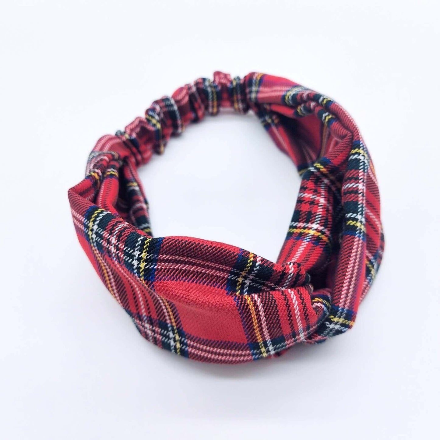 A soft, red traditional tartan, plaid, check, elasticated fabric headband, with a turban twist design at the front.