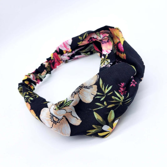 A soft, black viscose, floral print, turban twist headband with large flowers in pink, yellow and peach.