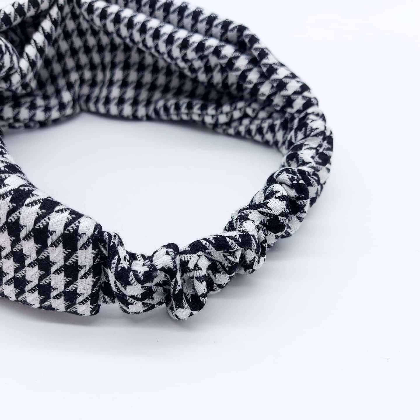 A luxurious, elasticated, turban twist headband made from a classic, houndstooth, black and white fabric.