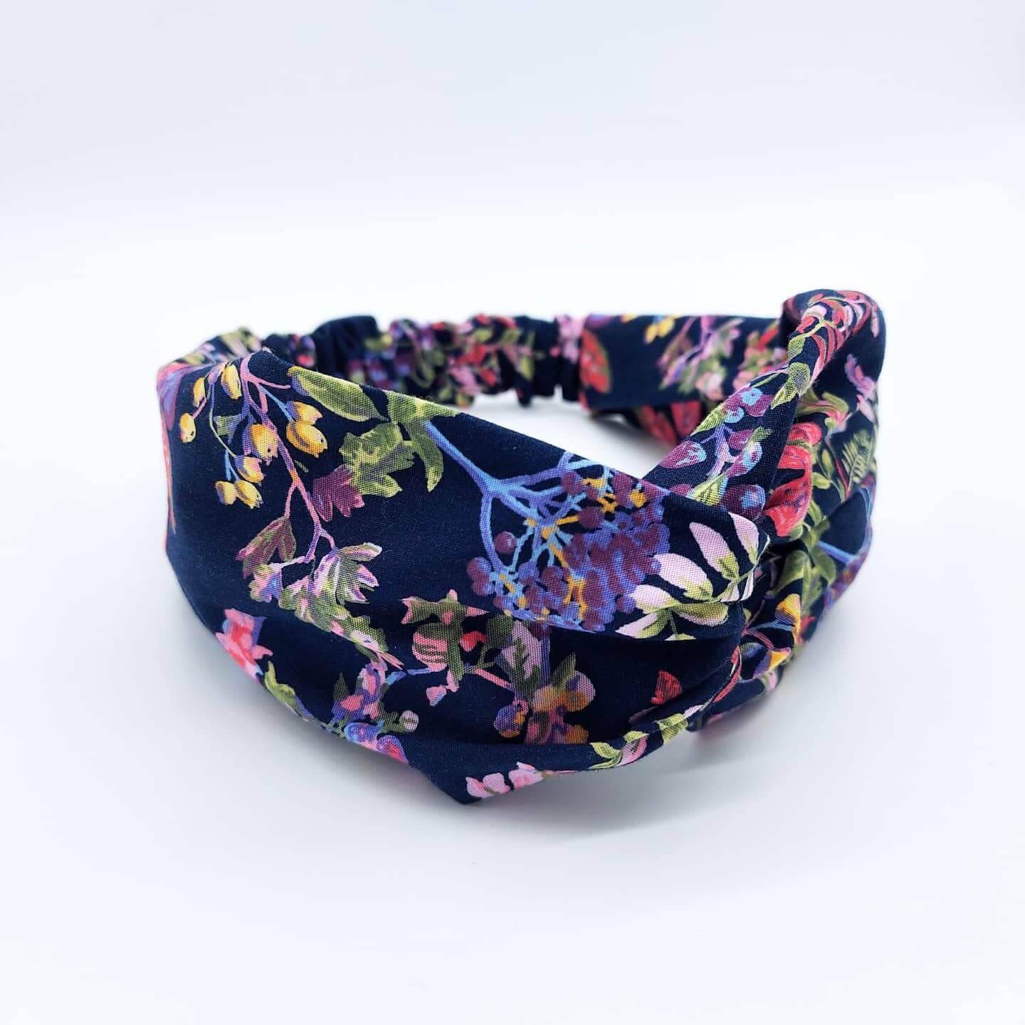 A pretty navy blue cotton, floral print turban twist headband with an elasticated panel at the back.