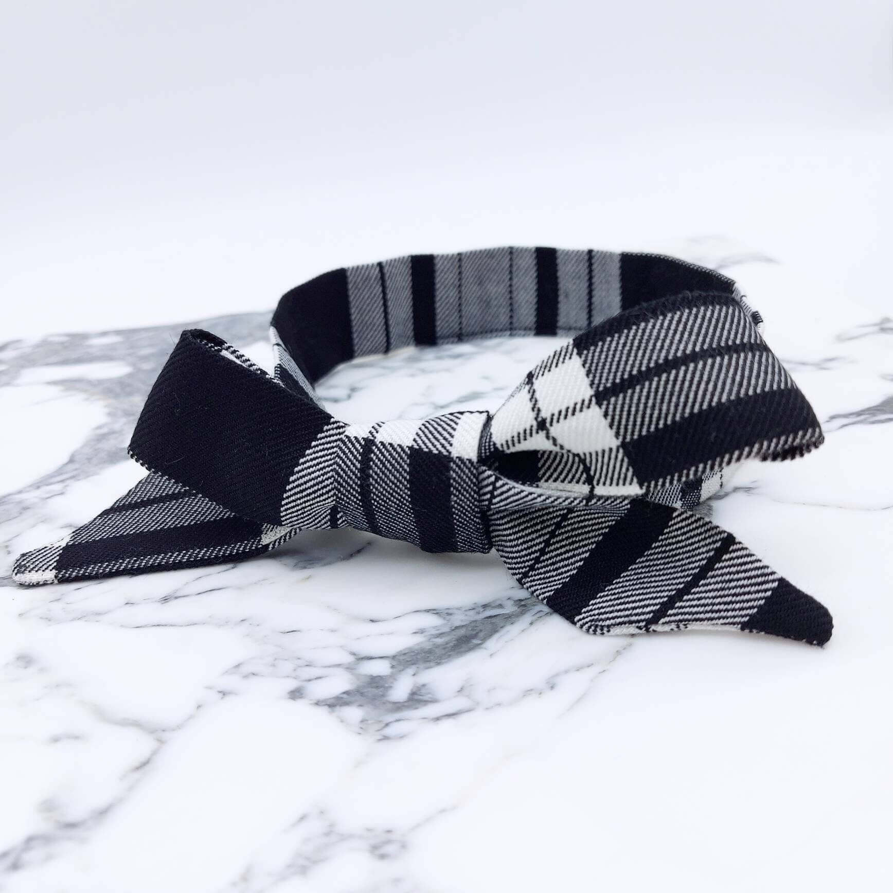 A tartan plaid, monochrome, black and white fabric, tie headband, tied in a pretty knot.