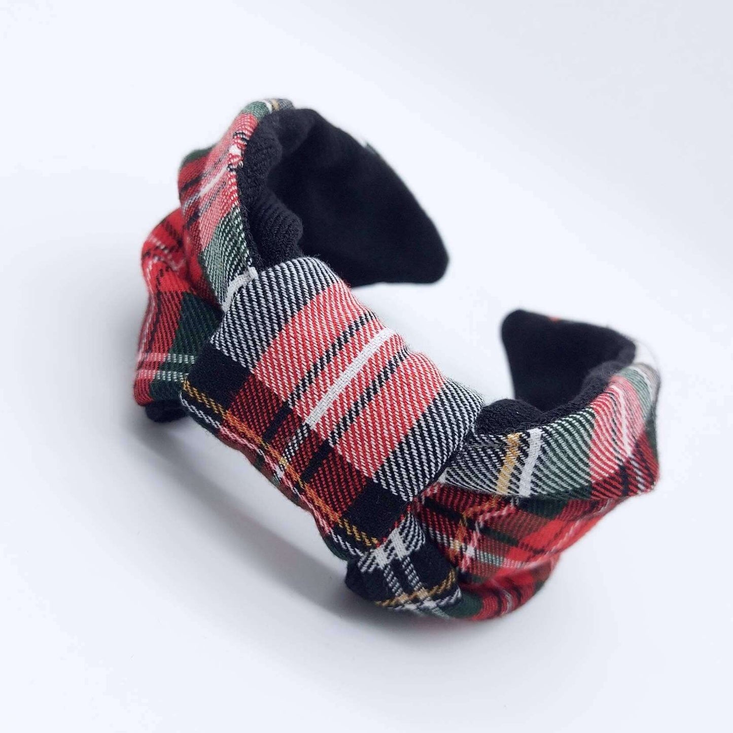 A bow-style, black and red tartan plaid fabric headband with plain black lining underneath