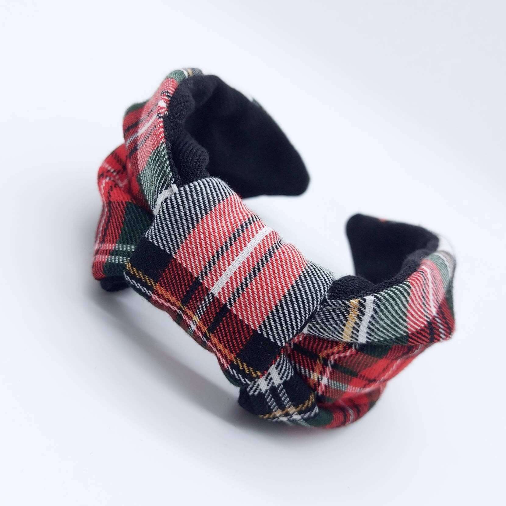 A bow-style, black and red tartan plaid fabric headband with plain black lining underneath