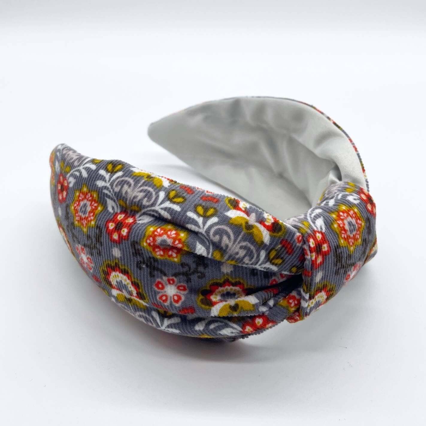 A bow-style, Scandinavian pale grey floral-print knot headband with an ice-white lining underneath.