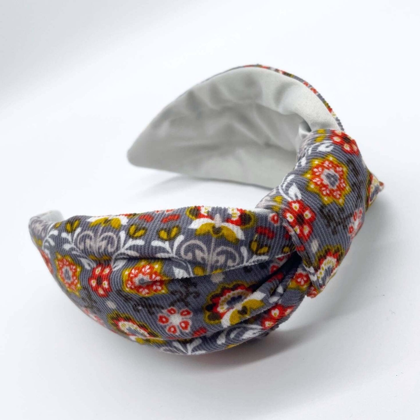 A bow-style, Scandinavian pale grey floral-print knot headband with an ice-white lining underneath.