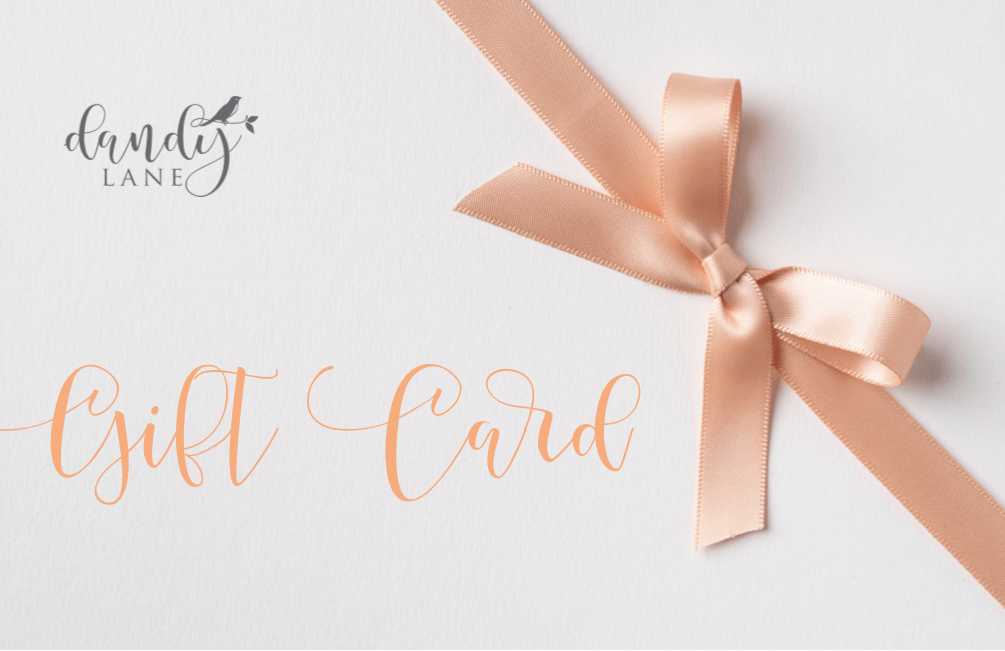 A pale coral pink gift card with the Dandy Lane logo and the text 'gift card'. A pink satin ribbon is in the top right corner.