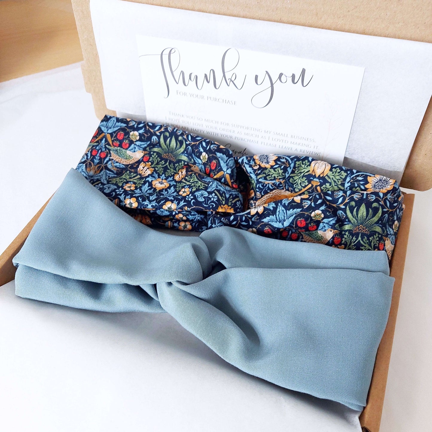Two, turban twist headbands, packaged in a brown gift box lined with tissue paper.