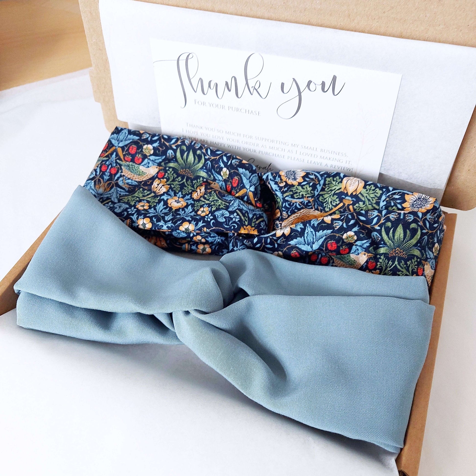 Two, turban twist headbands, packaged in a brown gift box lined with tissue paper.