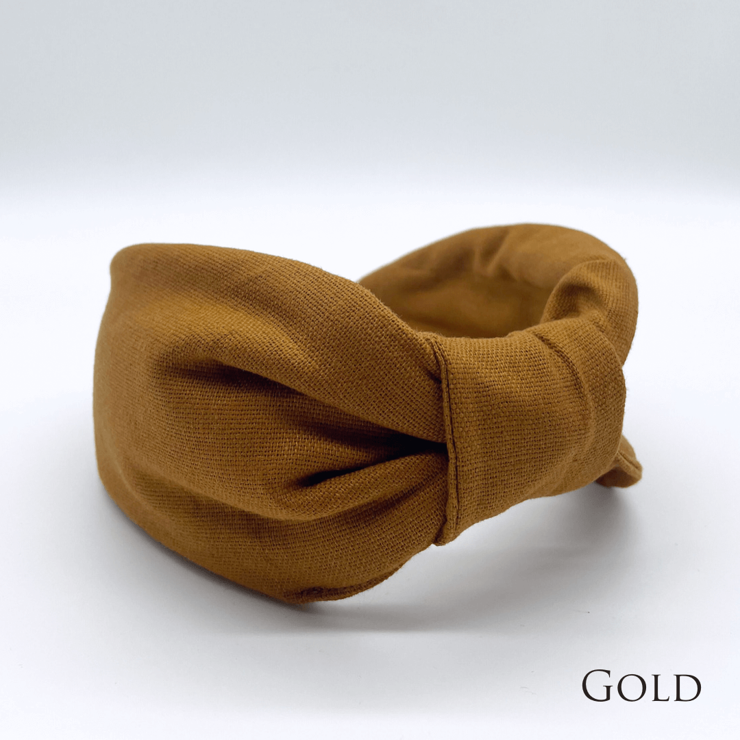 A gold linen knotted headband in a bow style.