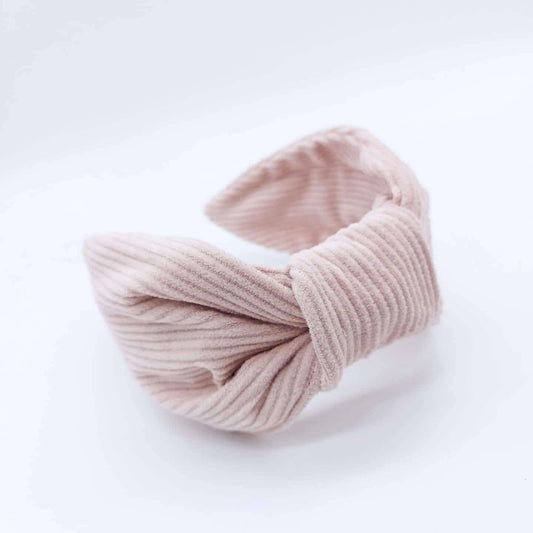 A pale-pink, corduroy headband in a bow-style.