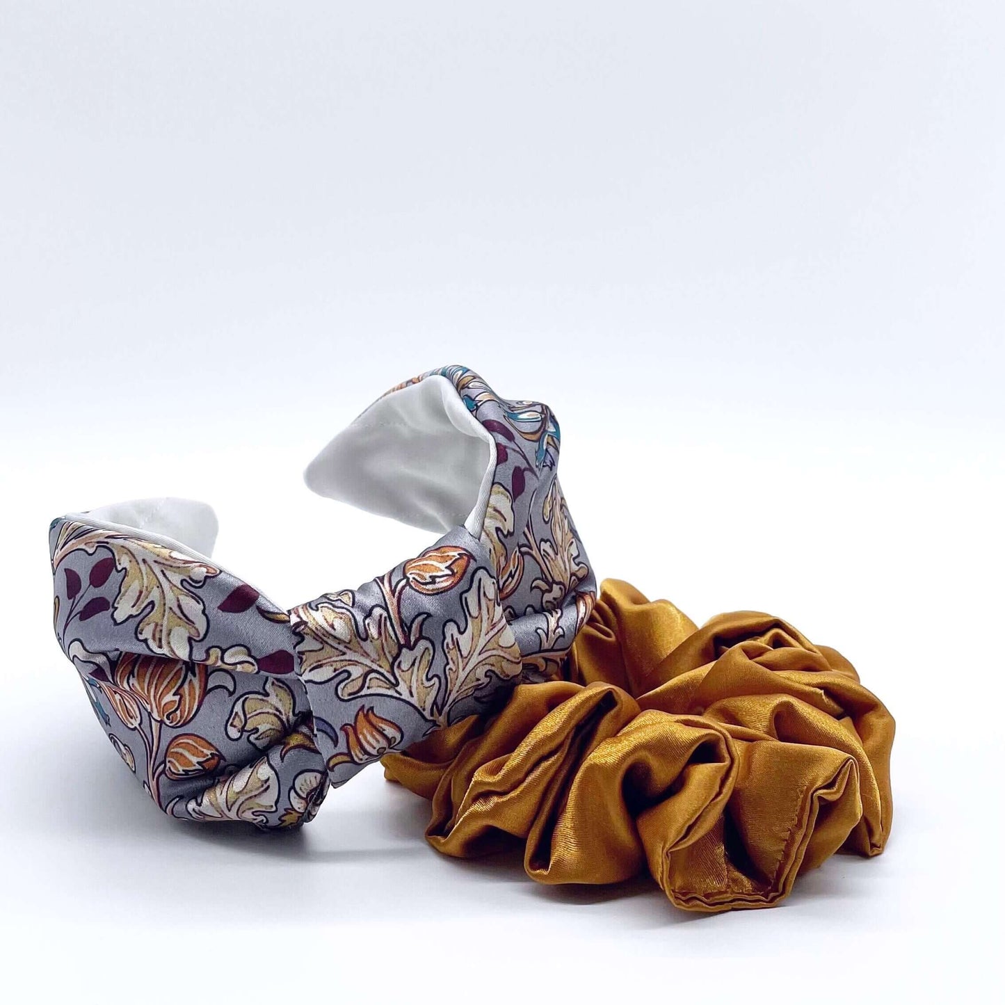 A beautiful grey, William Morris-inspired, patterned knot headband with a gold, satin scrunchie.