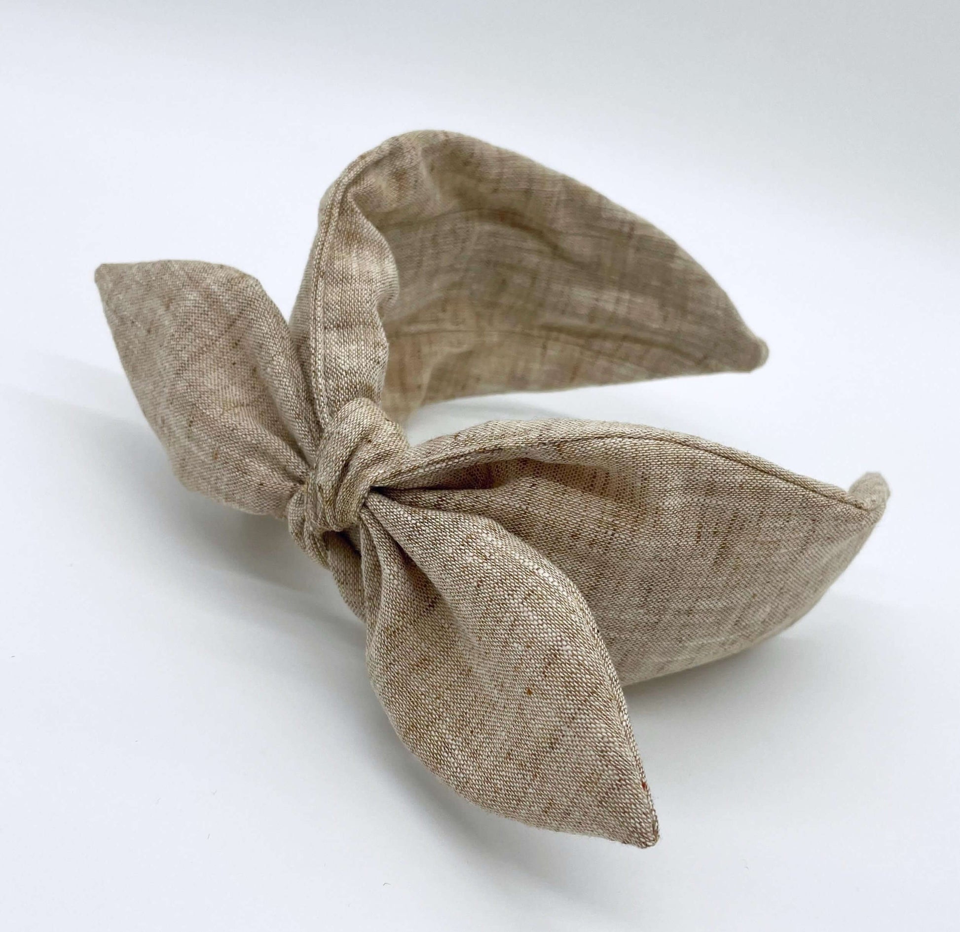 A natural coloured linen headban with a bow.