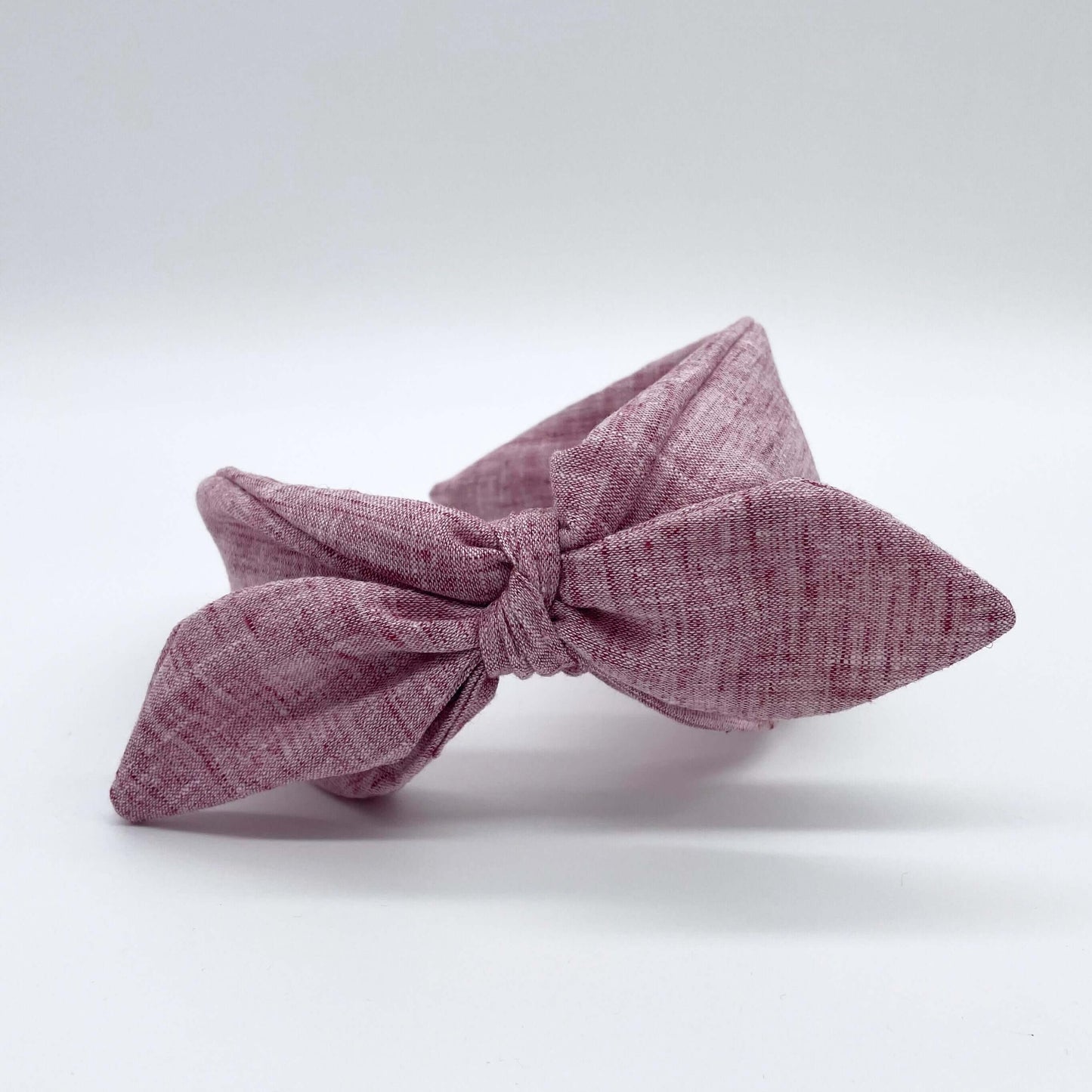 A pink coloured linen headban with a bow.