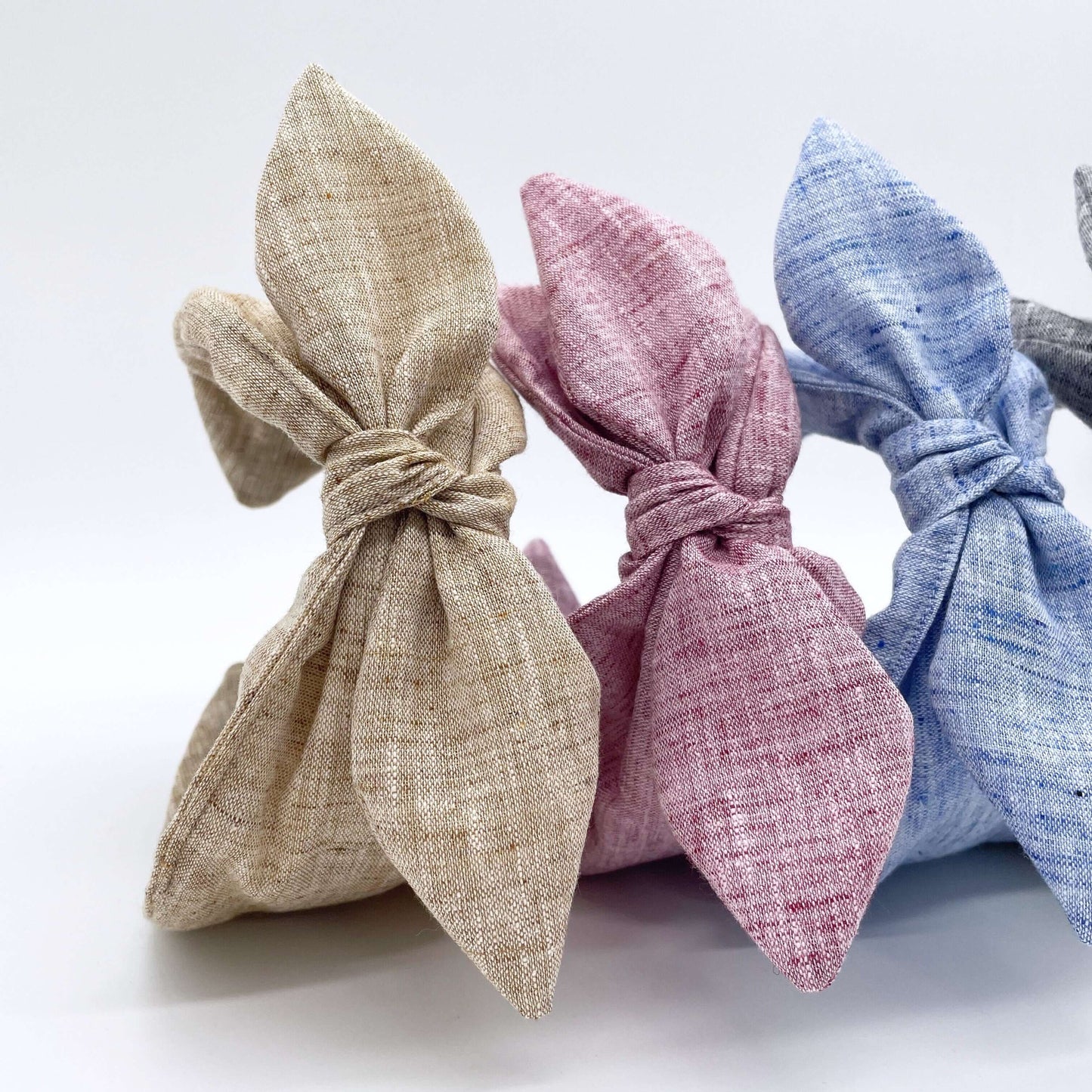 Three pretty linen fabric headbands with bows, pink, natural, blue.