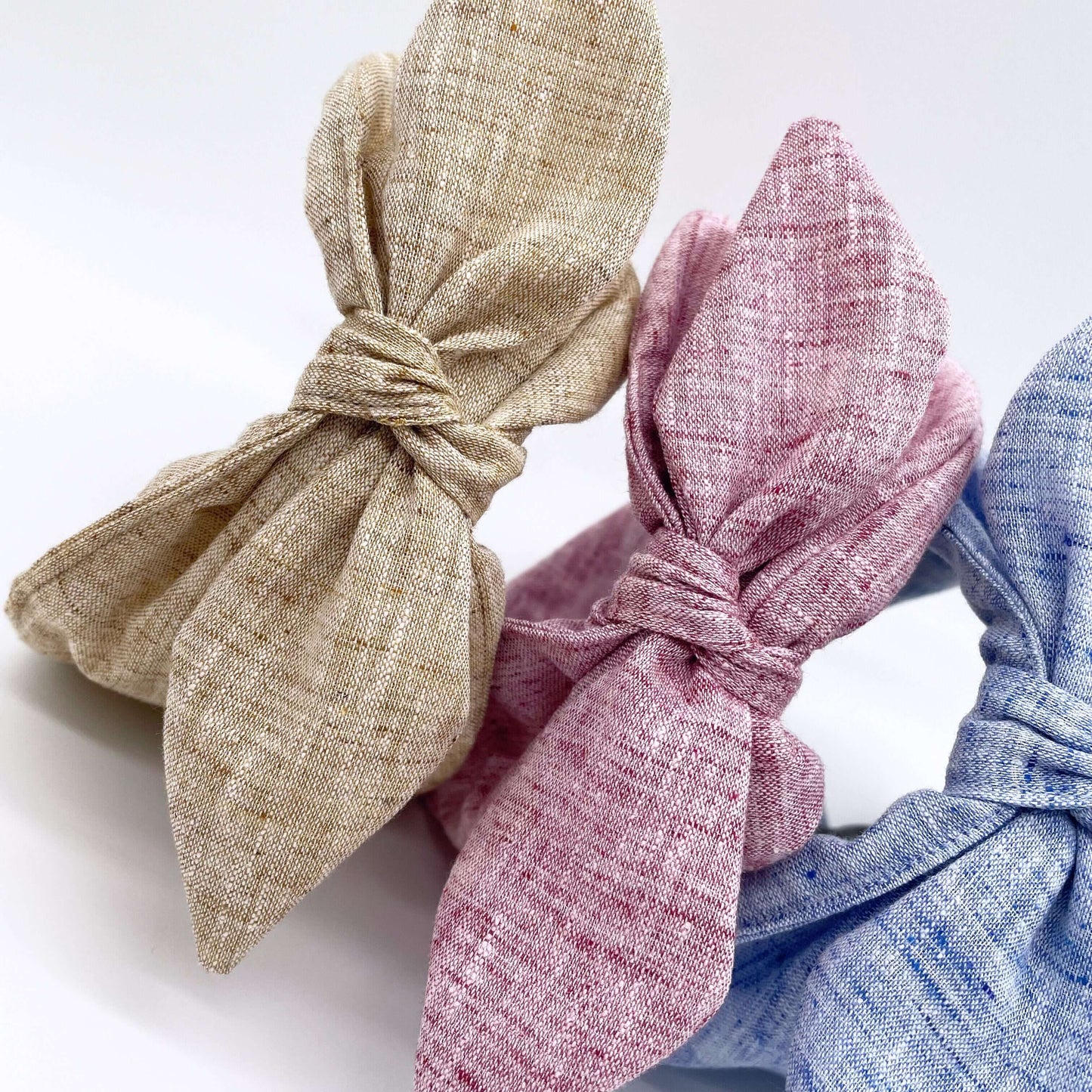 Three pretty linen fabric headbands with bows, pink, natural, blue.