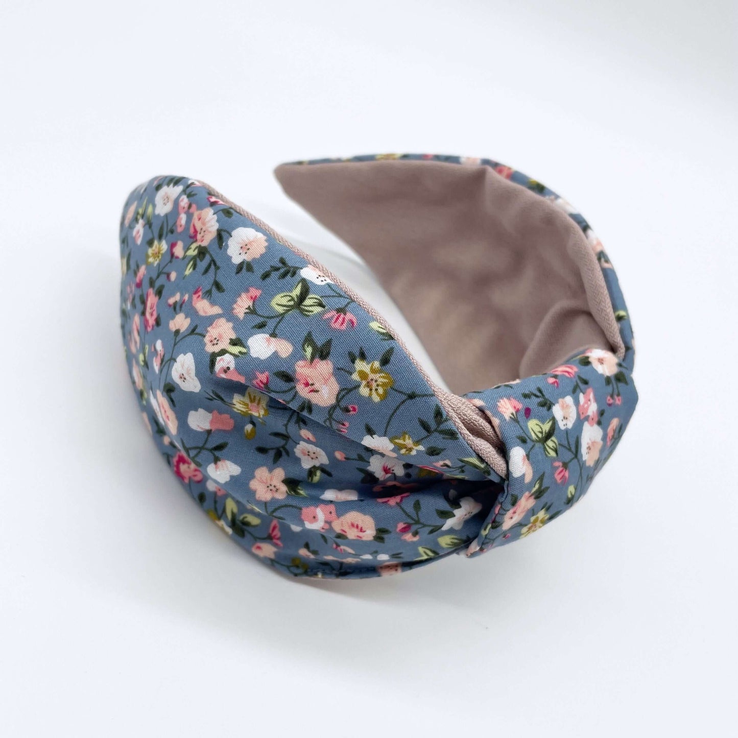 A pink, blue and white ditsy print knot-style headband on a white background