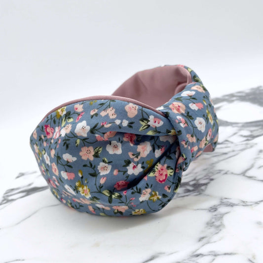 A pink, blue and white ditsy print knot-style headband on a marble slab.