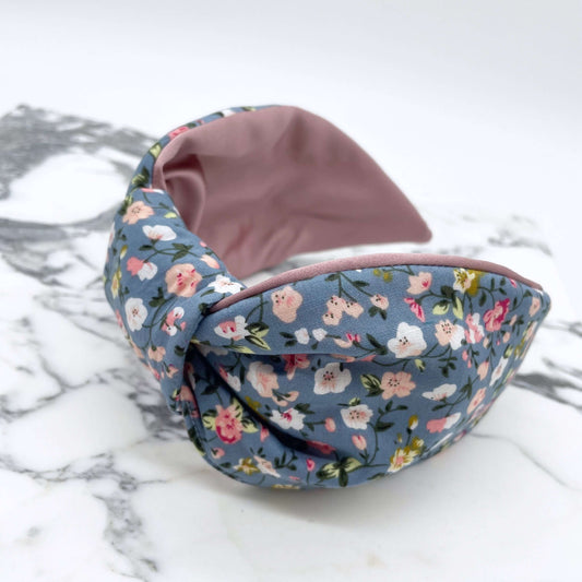 A pink, blue and white ditsy print knot-style headband on a marble slab.