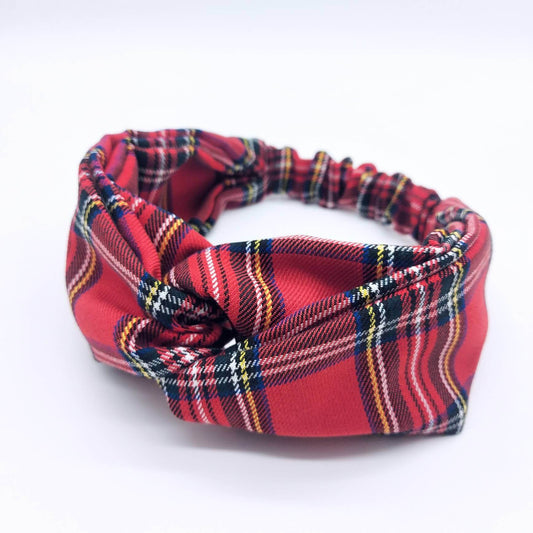A soft, red traditional tartan, plaid, check, elasticated fabric headband, with a turban twist design at the front.