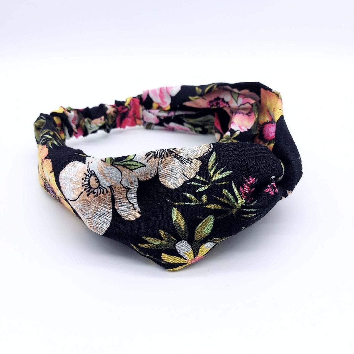 A soft, black viscose, floral print, turban twist headband with large flowers in pink, yellow and peach.