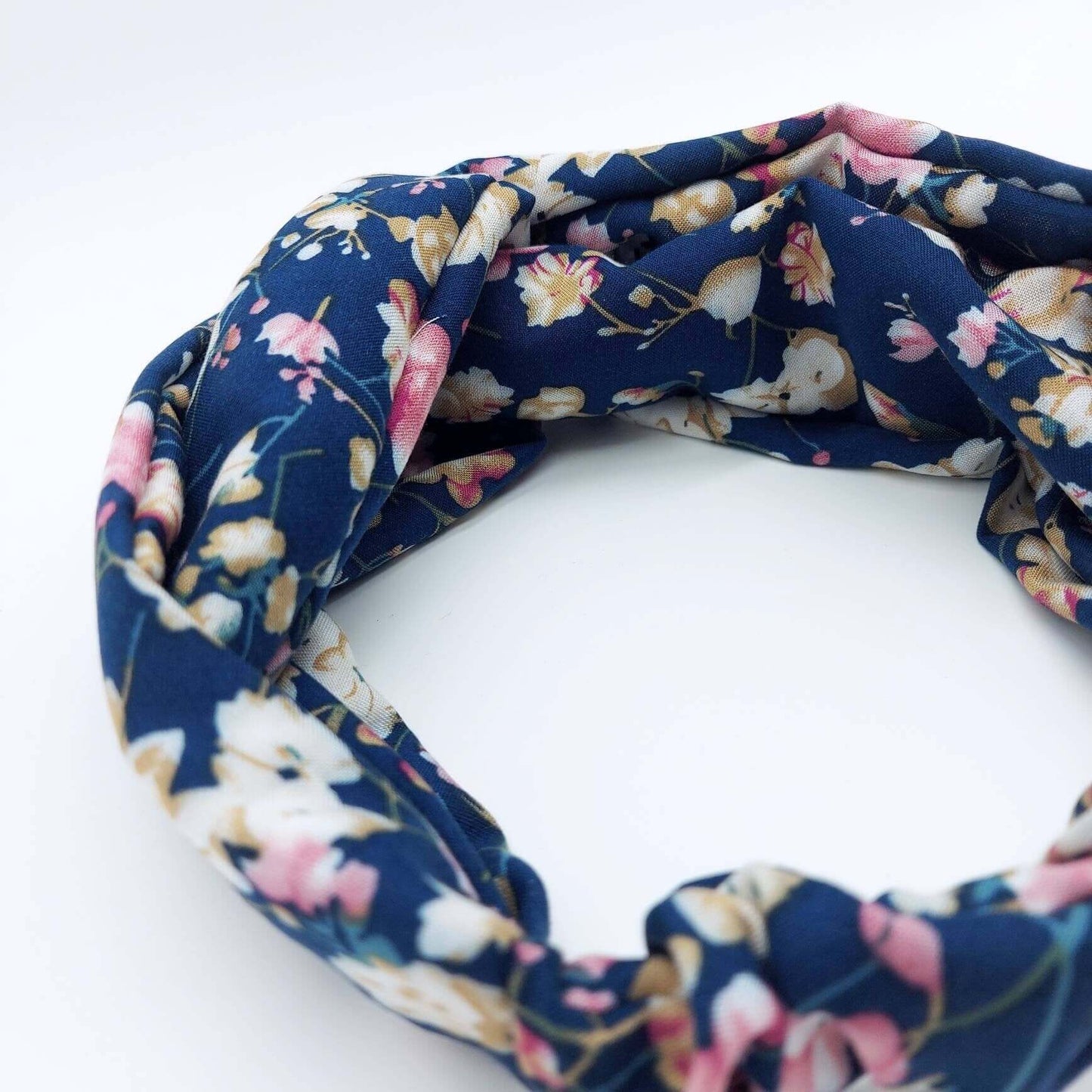 A soft, navy floral, turban twist headband with pops of pink, cream and yellow.