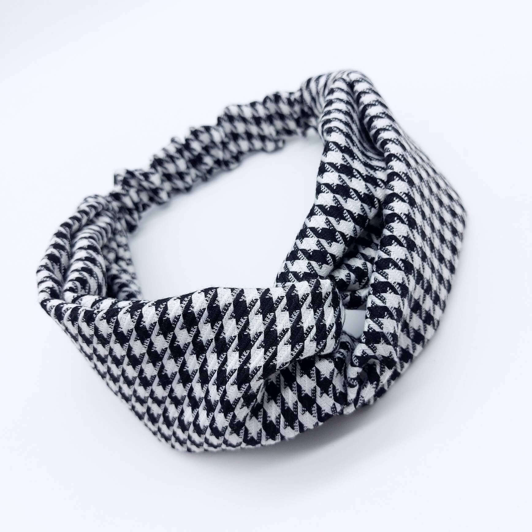 A luxurious, elasticated, turban twist headband made from a classic, houndstooth, black and white fabric.