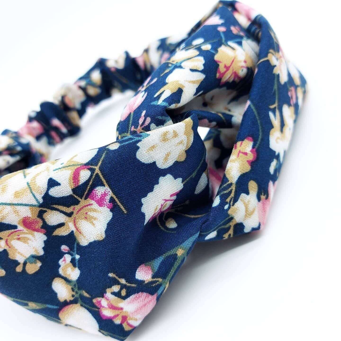 A soft, navy floral, turban twist headband with pops of pink, cream and yellow.