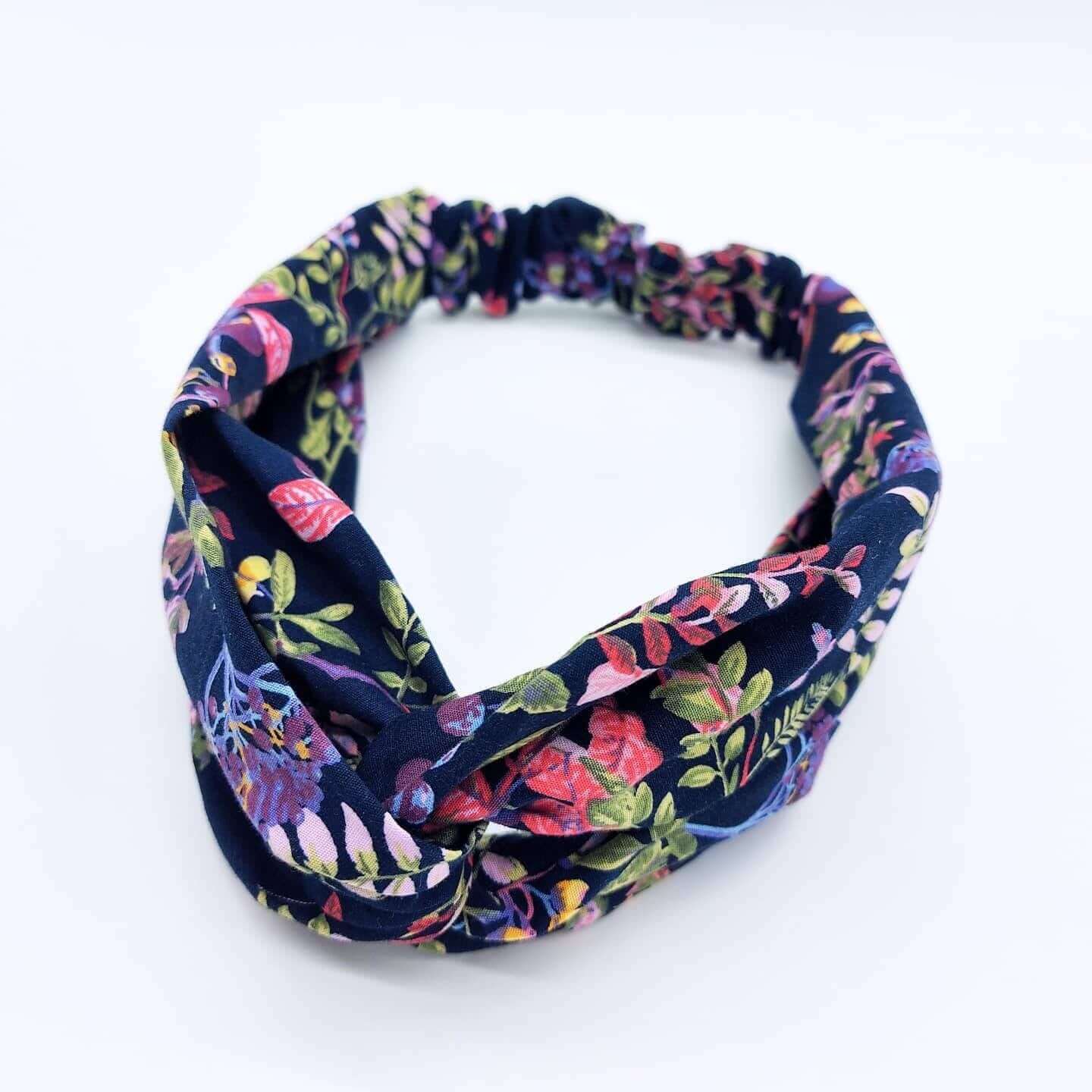 A pretty navy blue cotton, floral print turban twist headband with an elasticated panel at the back.