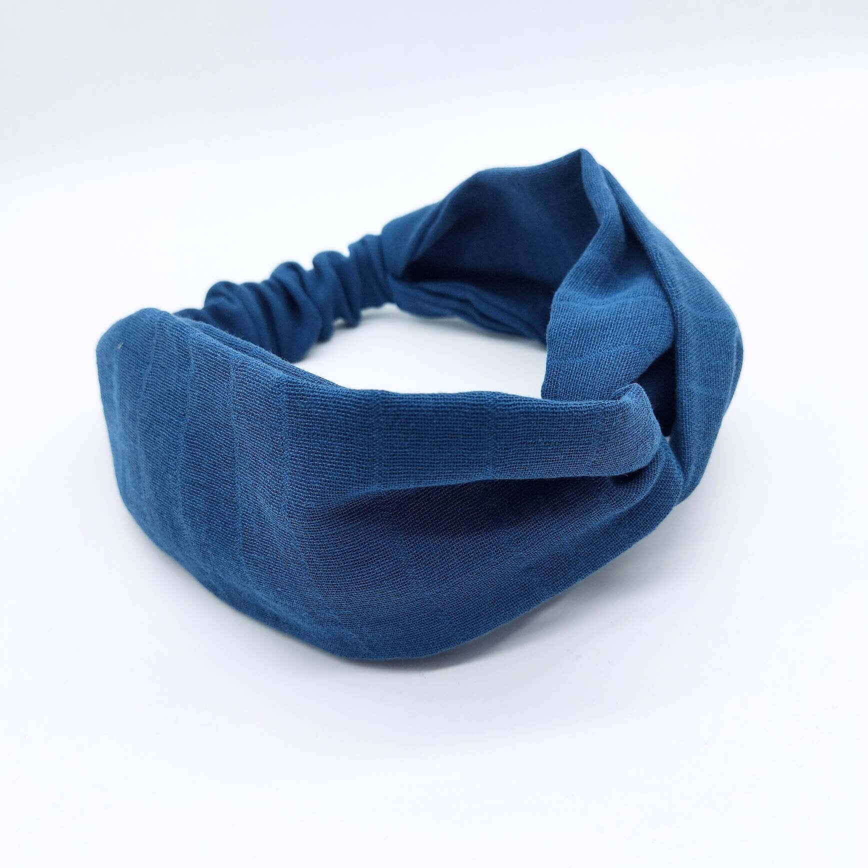A soft, teal blue, muslin cotton, turban twist headband with an elasticated panel at the back.