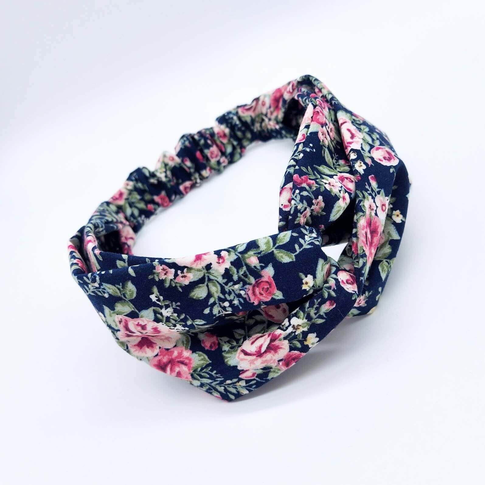 A navy blue, ditsy floral, cotton turban twist headband with an elasticated panel at the back.