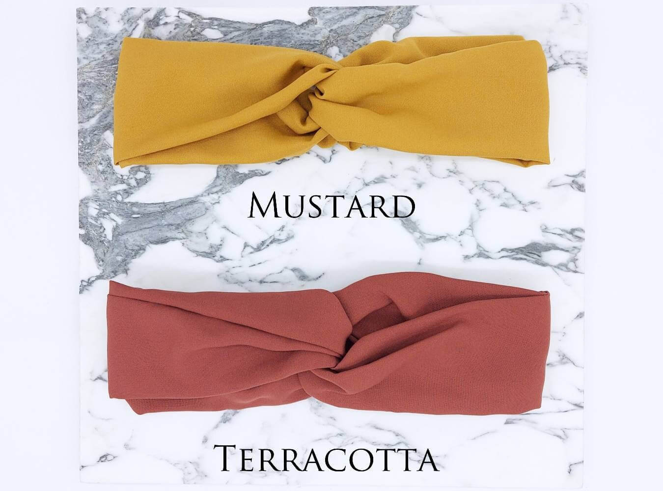 Two soft, viscose, elasticated turban twist headbands in mustard yellow and terracotta.