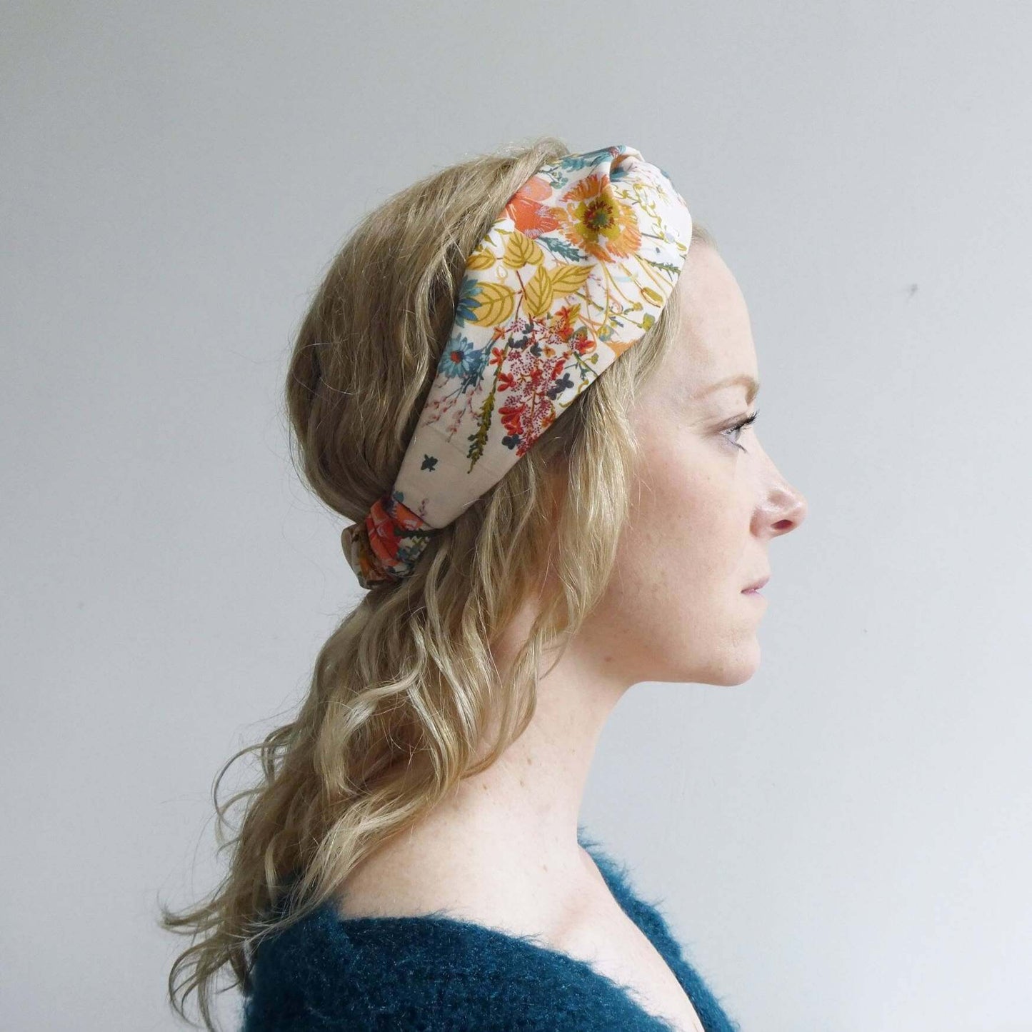Model wears a pretty cream cotton, floral print turban twist headband with an elasticated panel at the back.