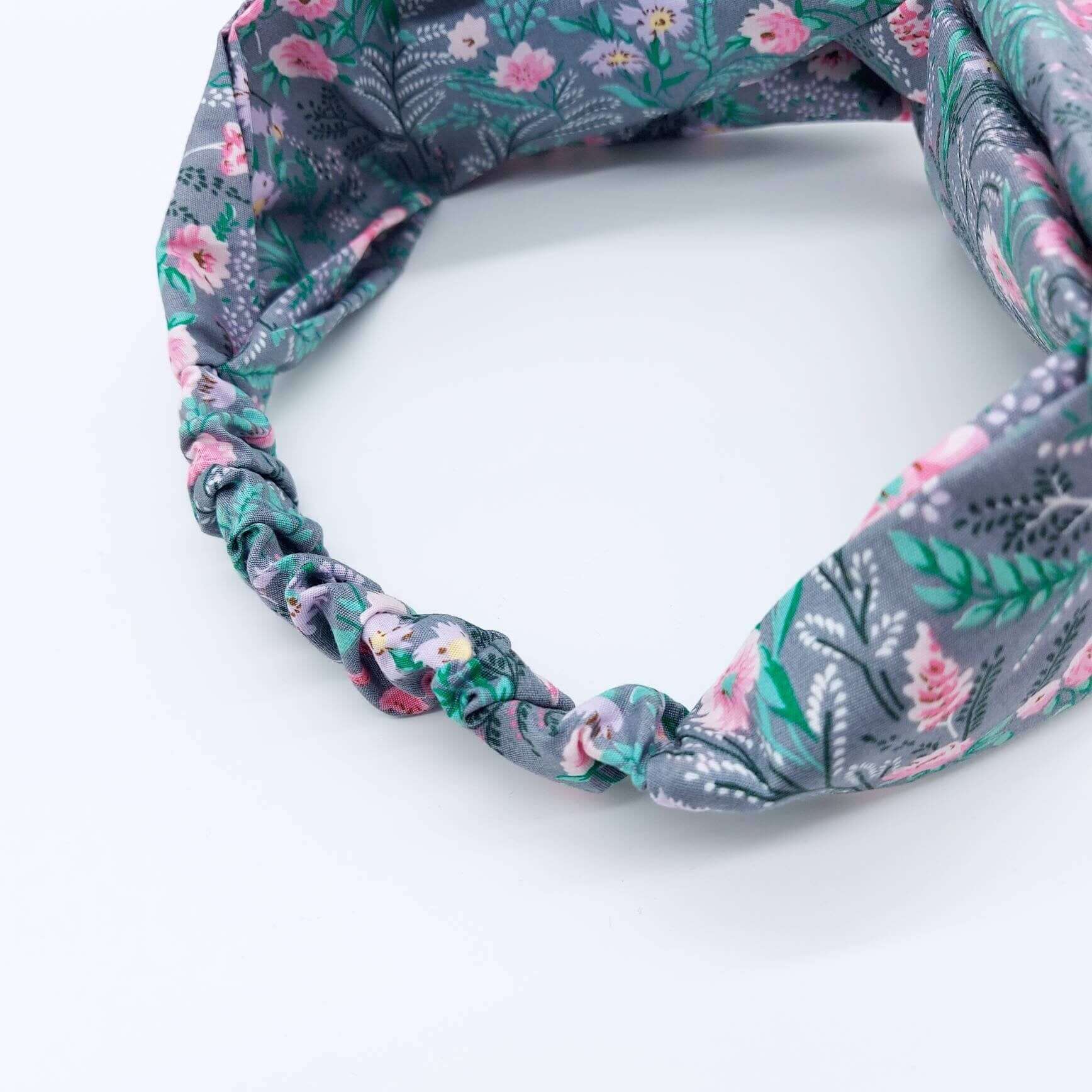 A pretty grey cotton, ditsy floral print turban twist headband with an elasticated panel at the back.