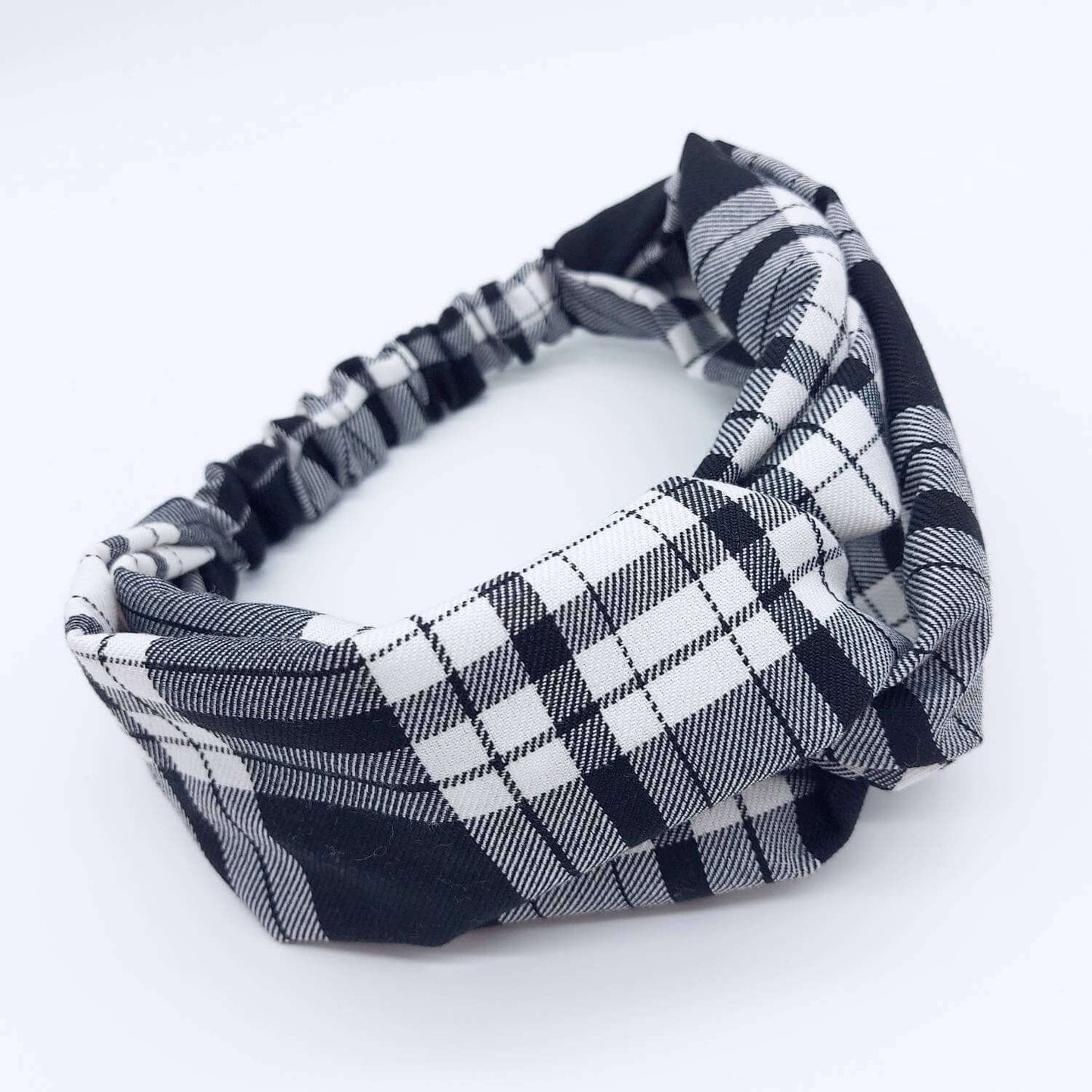 A soft, black and white tartan plaid check, turban twist headband with an elasticated panel at the back.