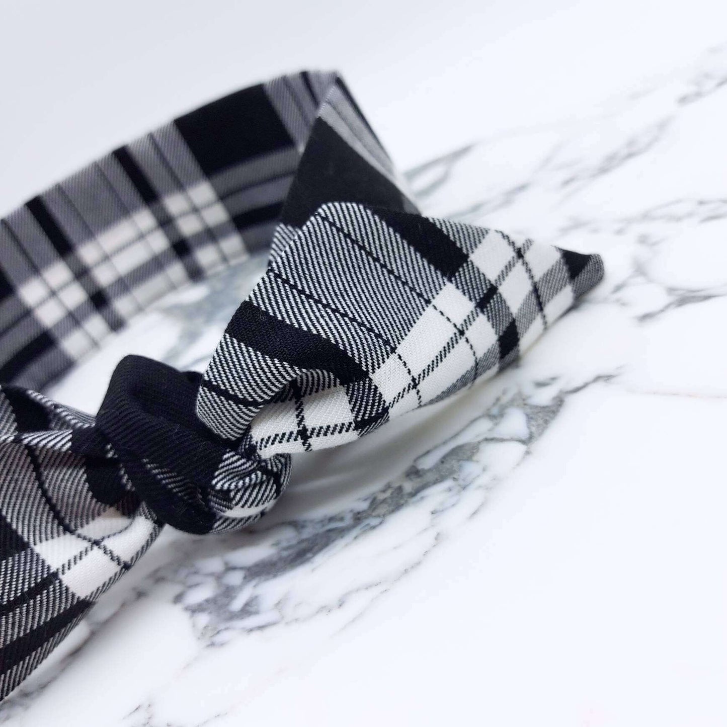 A tartan plaid, monochrome, black and white fabric, tie headband, tied in a pretty knot.