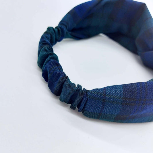 A soft, black and blue plaid tartan check, elasticated fabric headband, with a turban twist design at the front.
