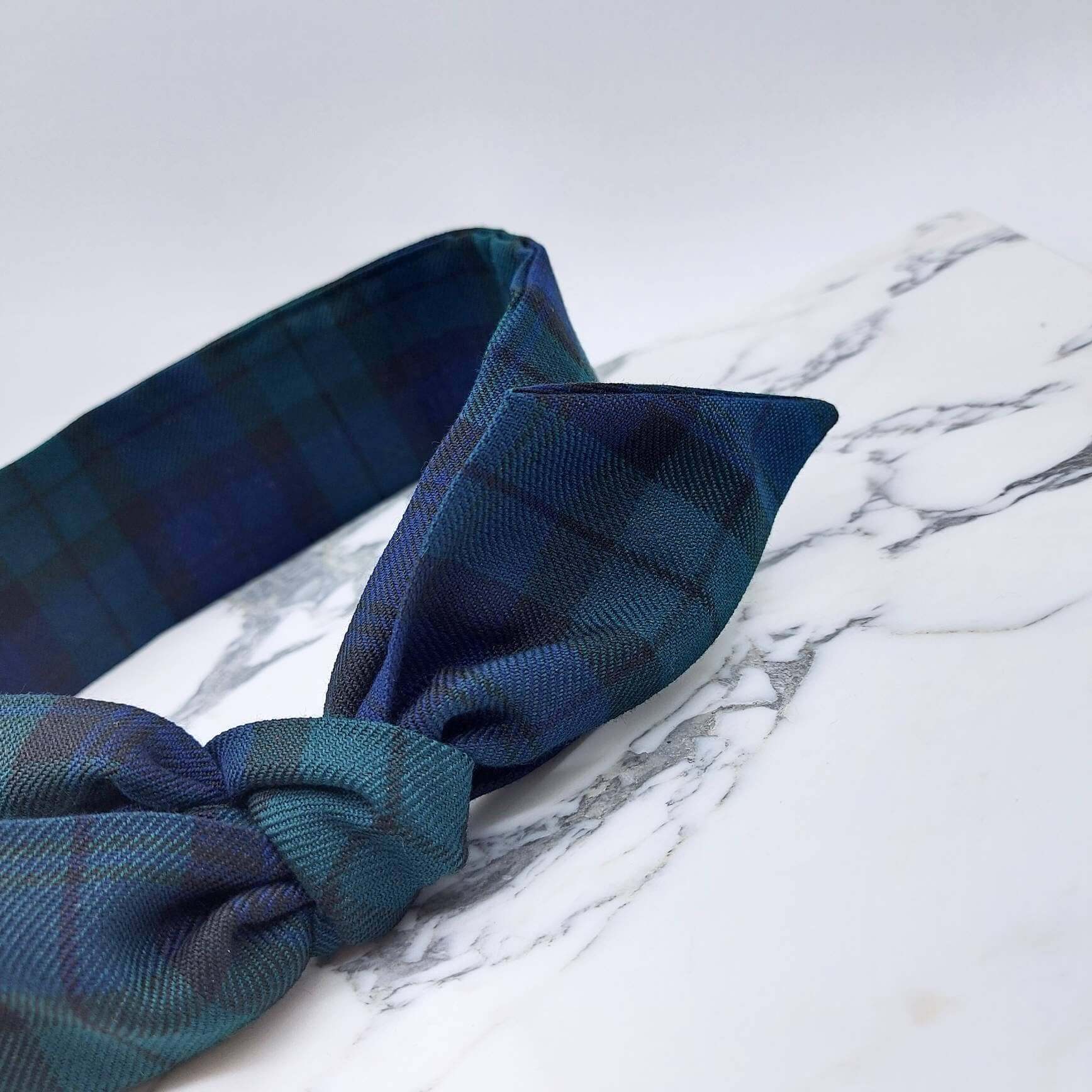 A black and navy blue tartan check fabric, tie headband, tied in a pretty knot.