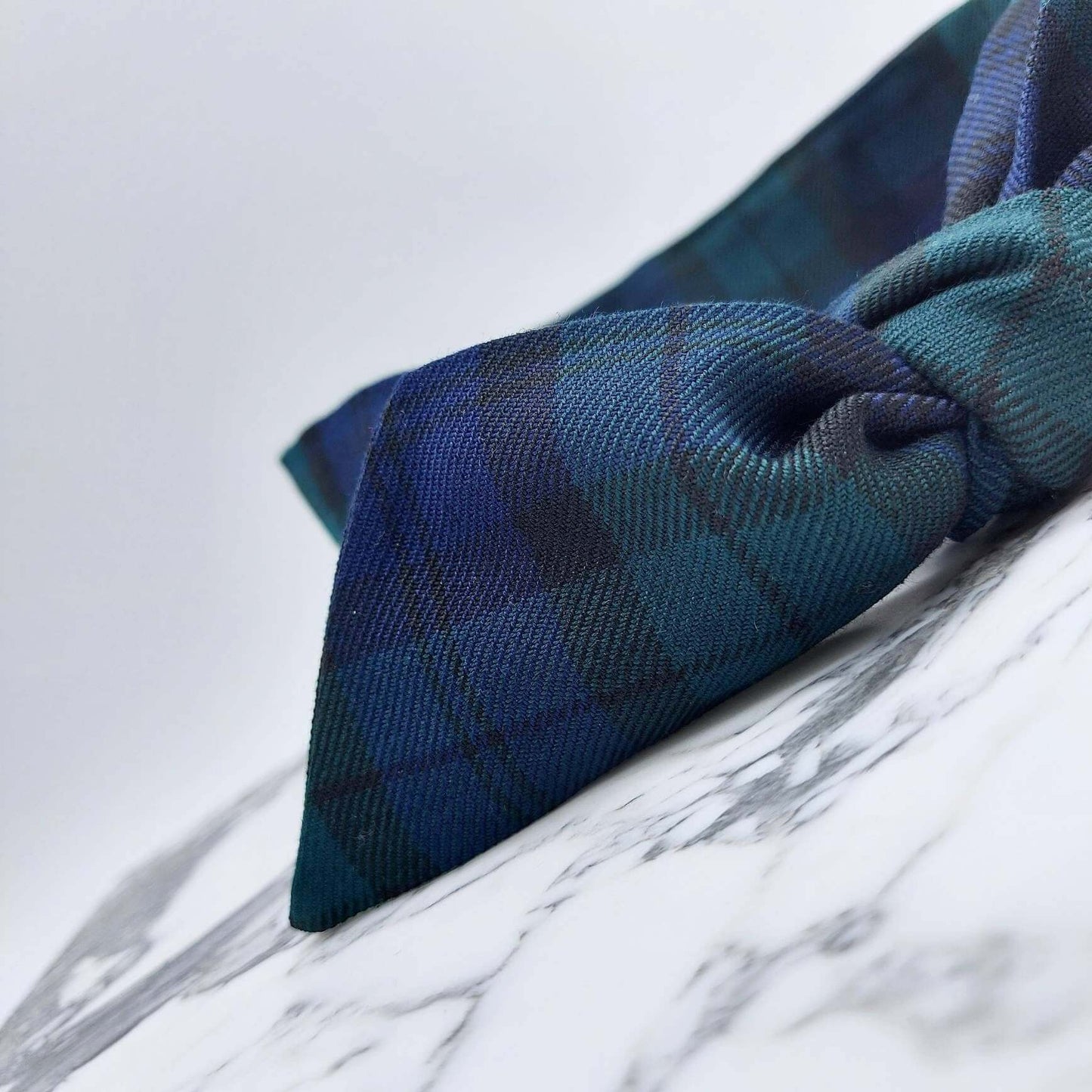 A black and navy blue tartan check fabric, tie headband, tied in a pretty knot.