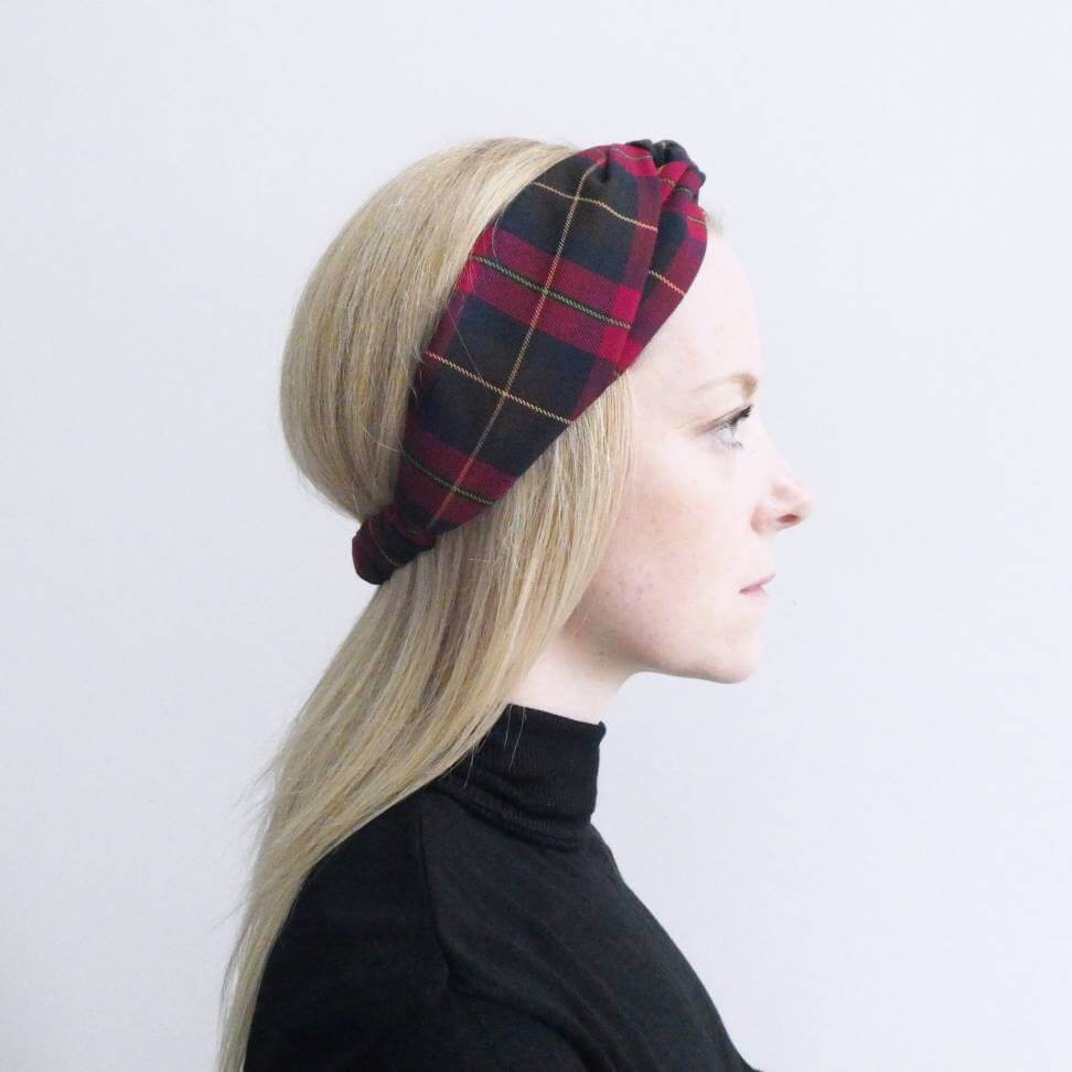 Model wears a soft, cranberry red, tartan, plaid, check, elasticated fabric turban twist headband.
