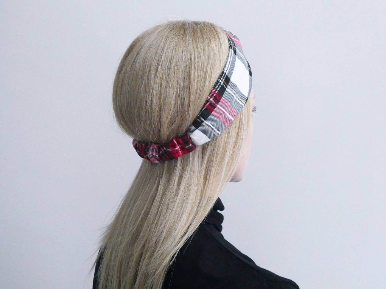 Model wears a soft, red and white, plaid tartan check, elasticated fabric headband, with a turban twist design at the front.