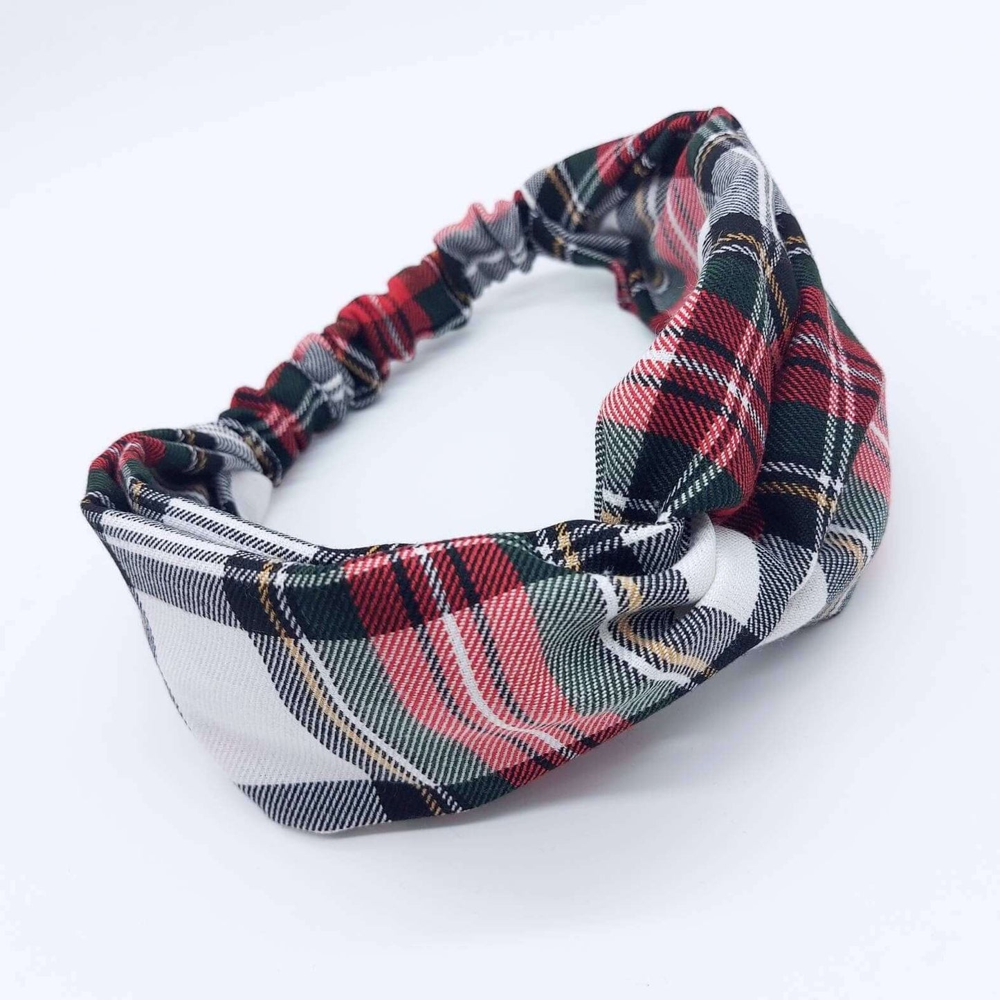 A soft, red and white, plaid tartan check, elasticated fabric headband, with a turban twist design at the front.