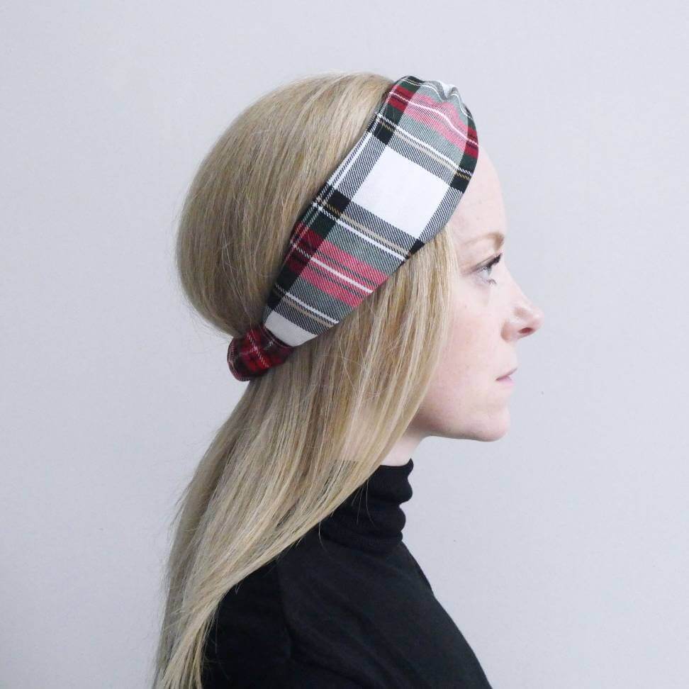 Model wears a soft, red and white, plaid tartan check, elasticated fabric headband, with a turban twist design at the front.