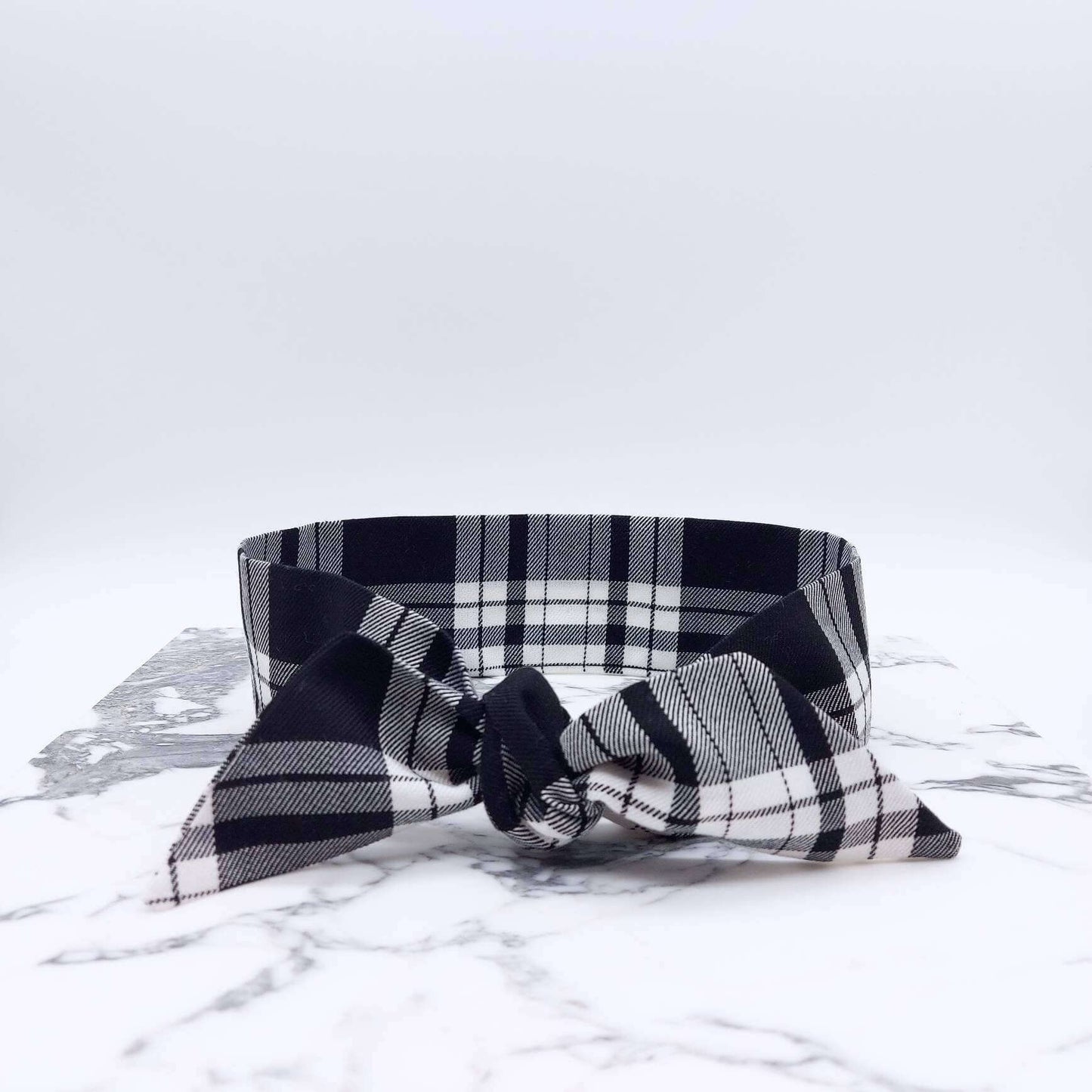 A tartan plaid, monochrome, black and white fabric, tie headband, tied in a pretty knot.