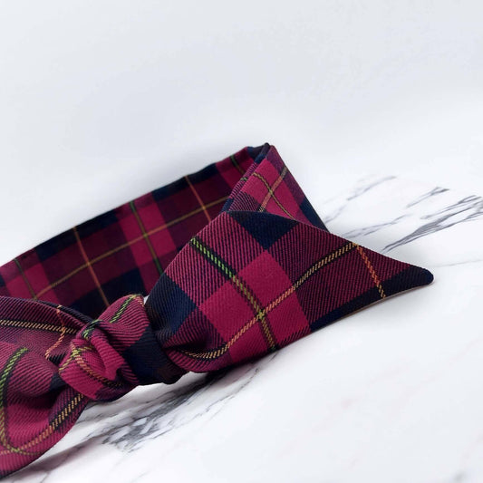 A dark cranberry and brown fabric, tartan paid tie headscarf, tied in a pretty knot.