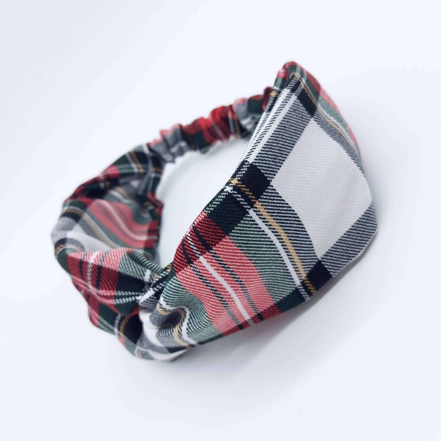 A soft, red and white, plaid tartan check, elasticated fabric headband, with a turban twist design at the front.