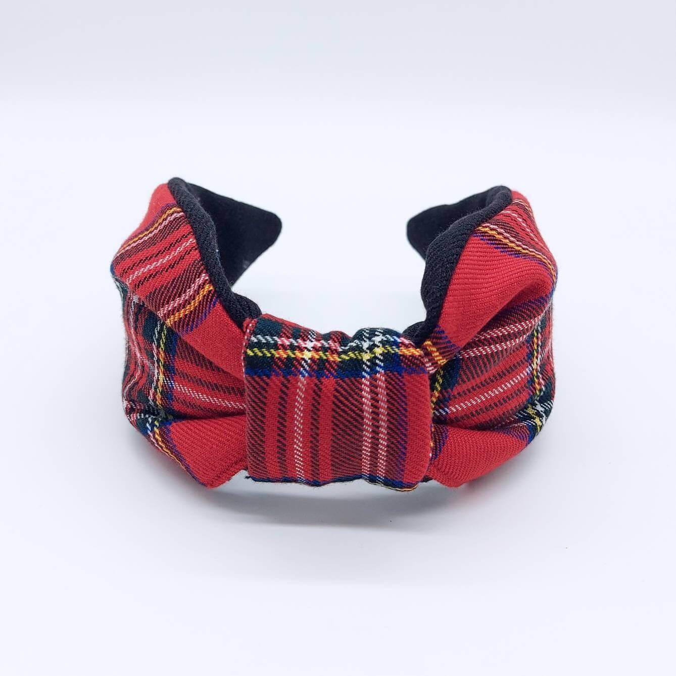 A bow-style, black and red tartan paid fabric headband with plain black lining underneath.