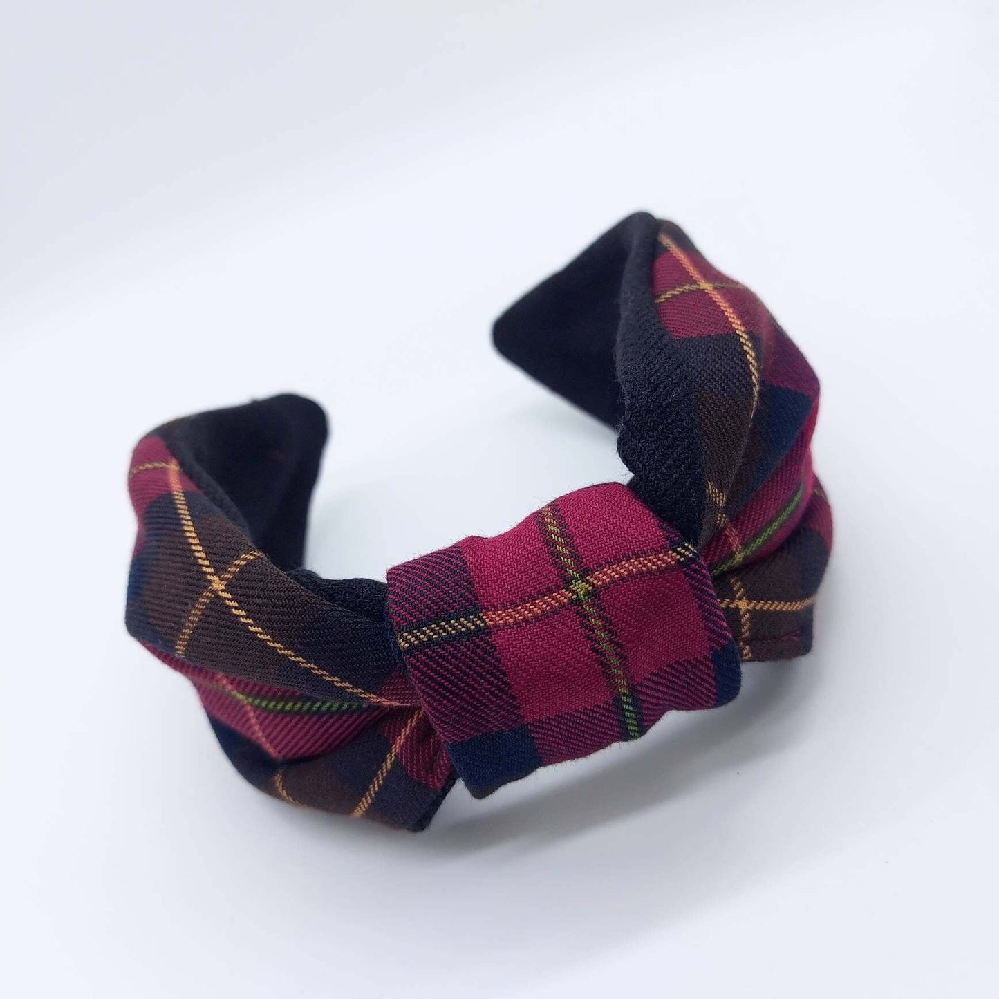 A bow-style, brown and red tartan plaid fabric knot headband with plain black lining underneath.