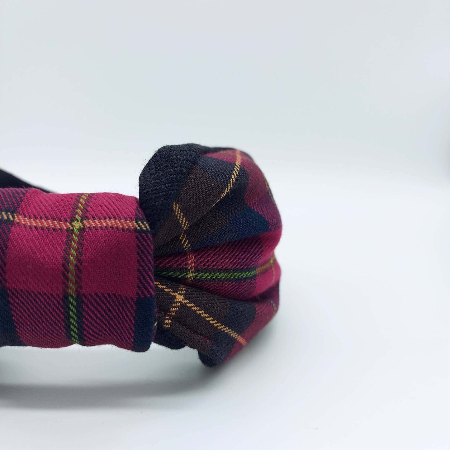 A bow-style, brown and red tartan plaid fabric knot headband with plain black lining underneath.